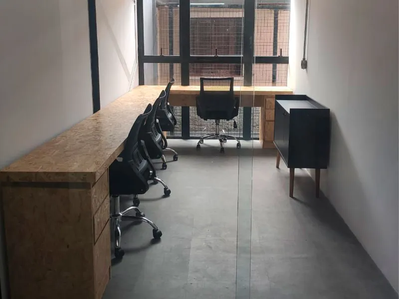 Sala privada com bancada longa, cadeiras e aparador, iluminada por janela ao fundo
