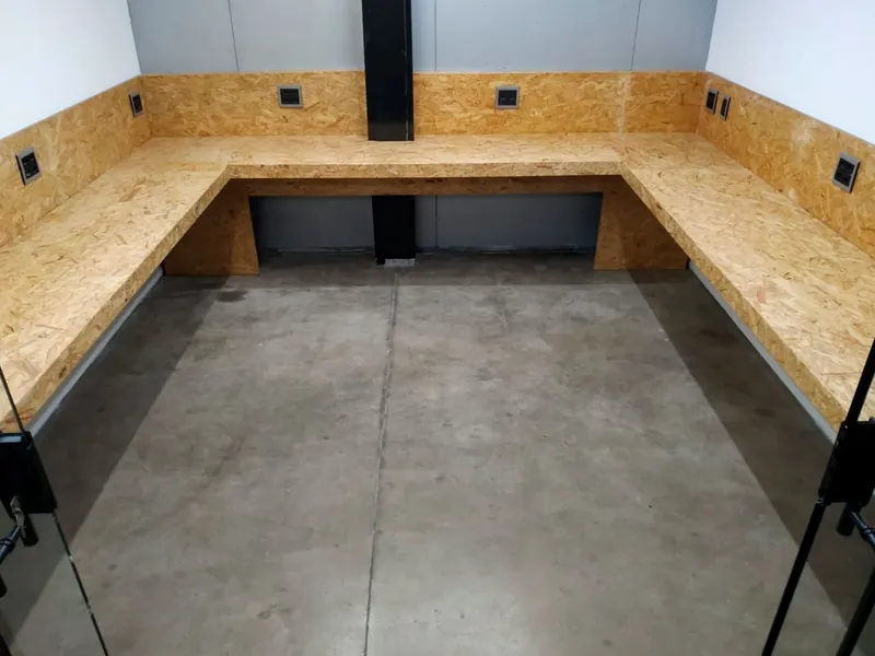 Sala privada com bancada em U de madeira e tomadas ao longo da parede, pronta para a equipe