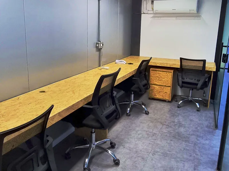 Sala privada com bancada em madeira para três pessoas, gaveteiro e ar-condicionado