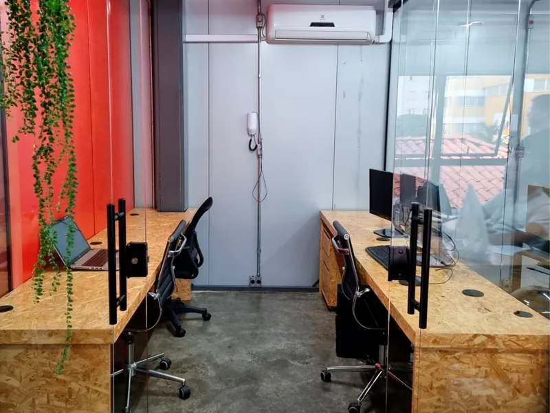 Salas privadas com portas de vidro, bancadas de madeira, computadores e ar-condicionado