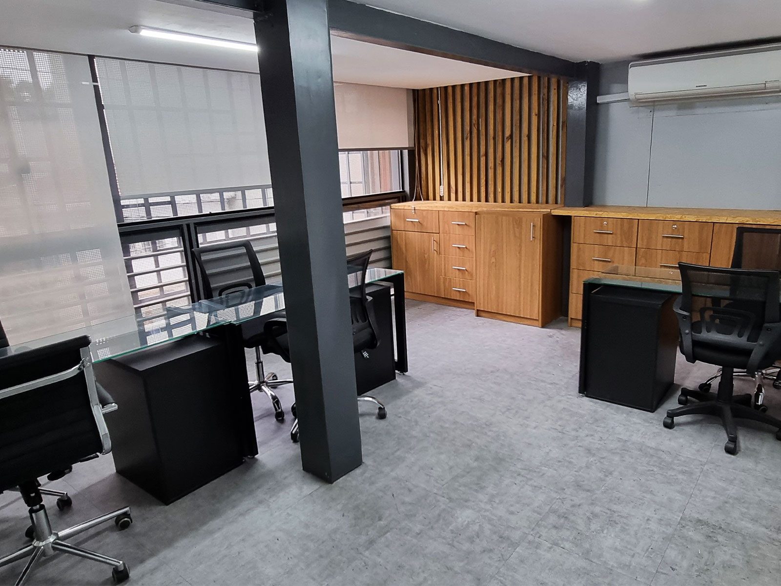 Sala privada mobiliada com mesas de vidro, cadeiras executivas, armários de madeira e ar-condicionado